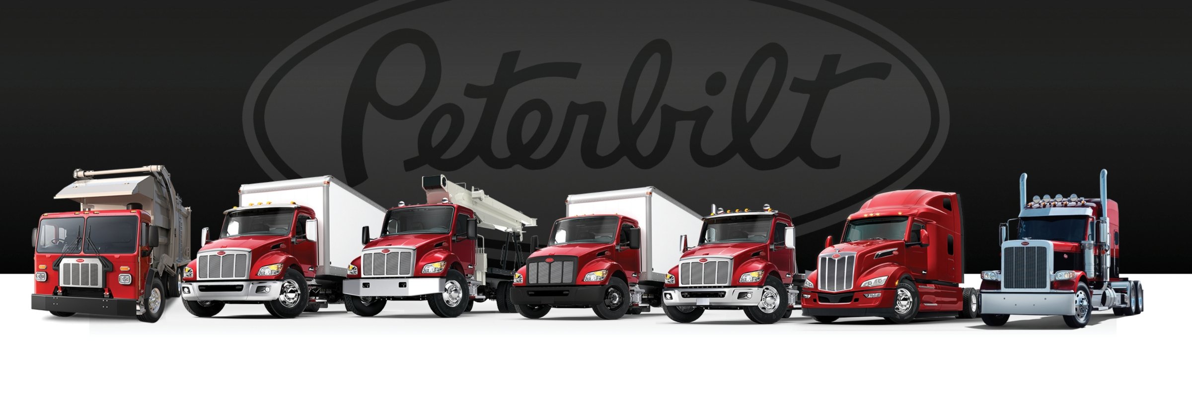 Peterbilt truck lineup with Peterbilt logo behind it | Peterbilt Trucks